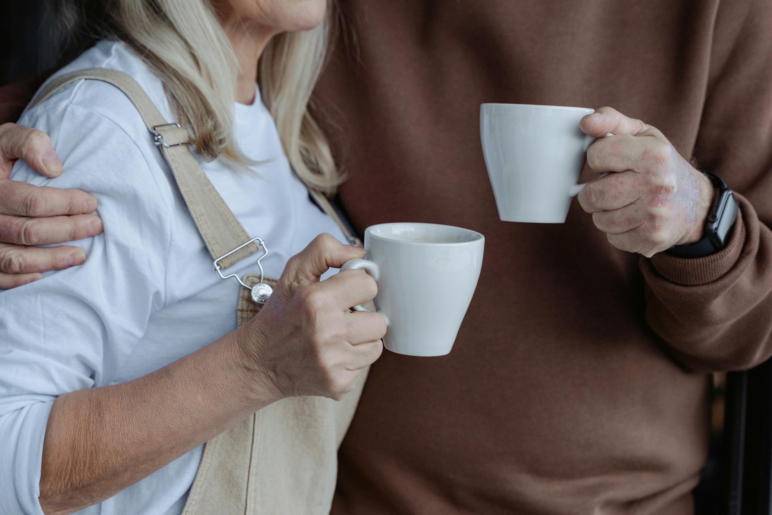 An elderly couple enjoying warm drinks in a cozy home setting.