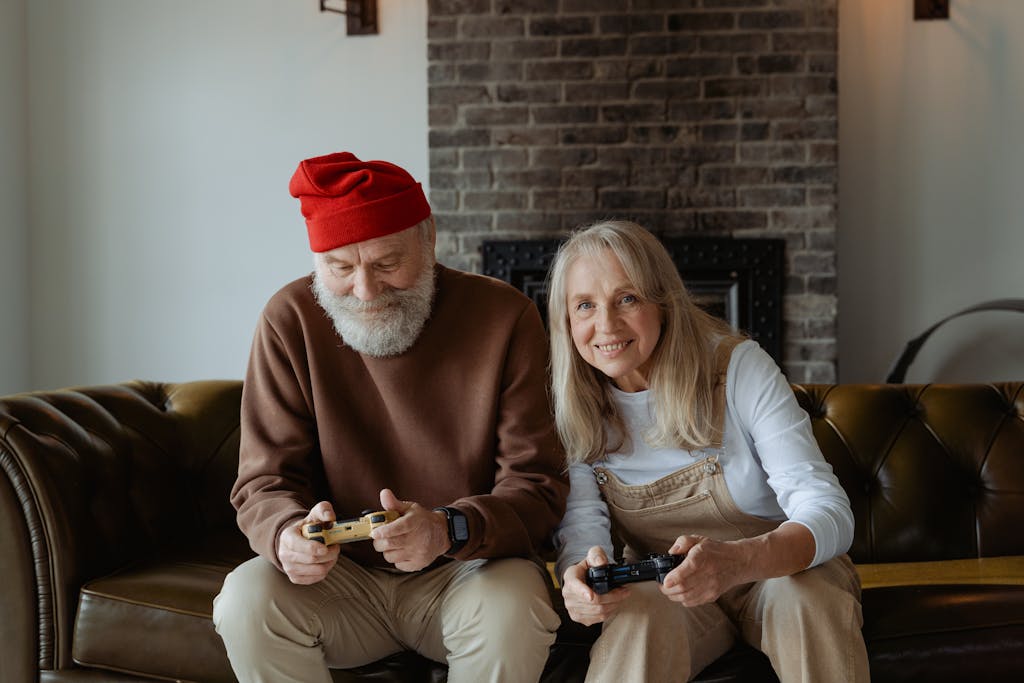 Elderly couple happily playing video games at home, embracing technology during retirement.
