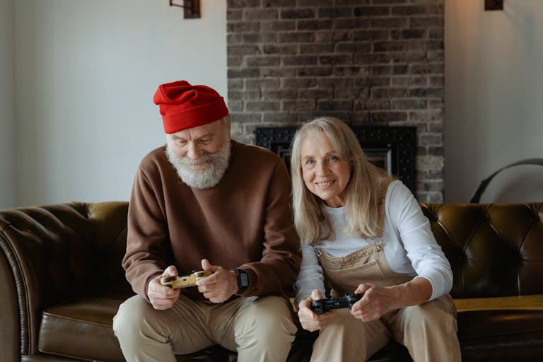 Elderly couple happily playing video games at home, embracing technology during retirement.