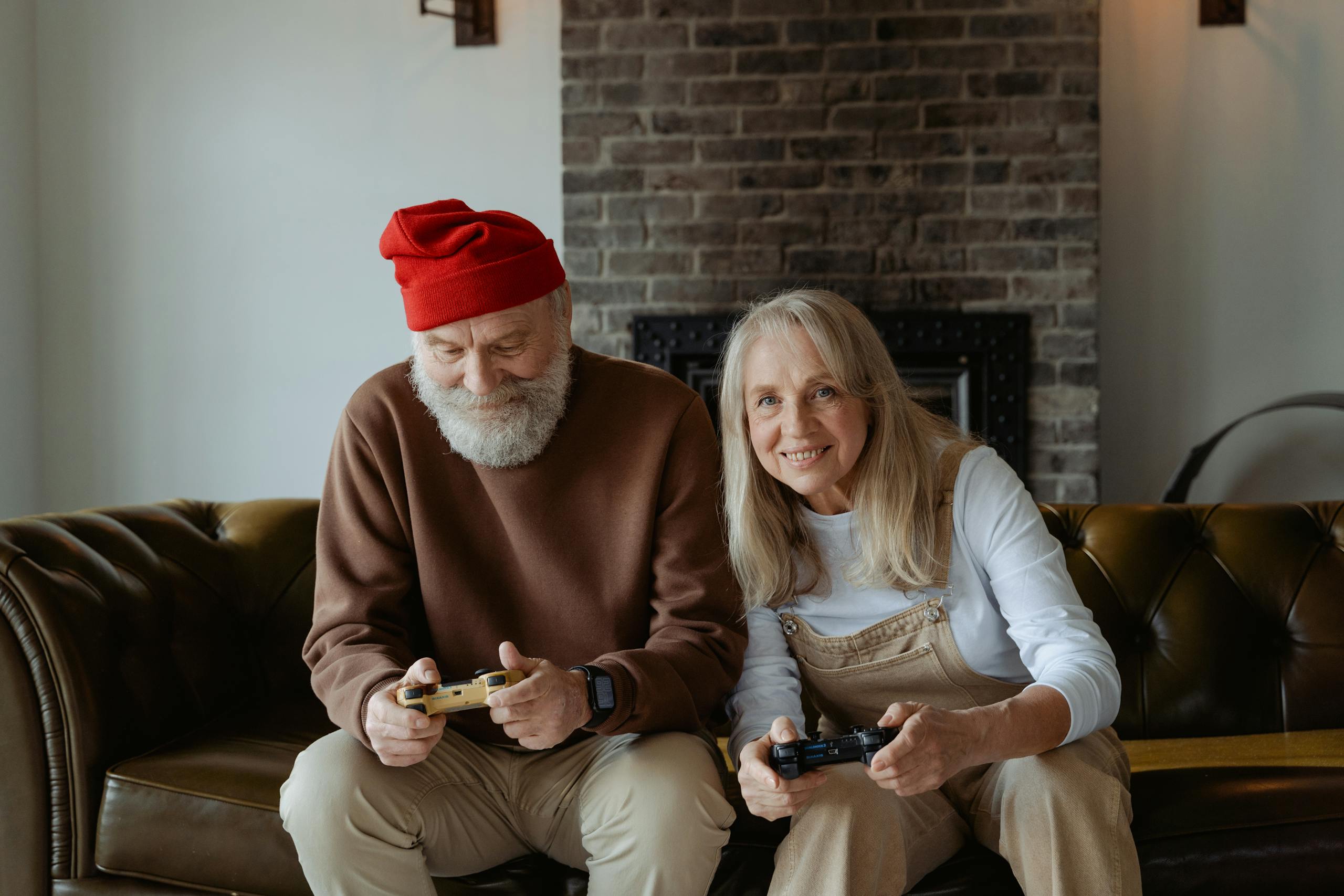 Elderly couple happily playing video games at home, embracing technology during retirement.