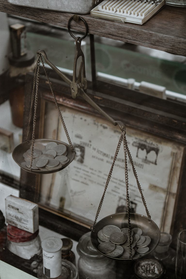Antique weighing scale with coins, set in a vintage collection room, highlighting historical charm.