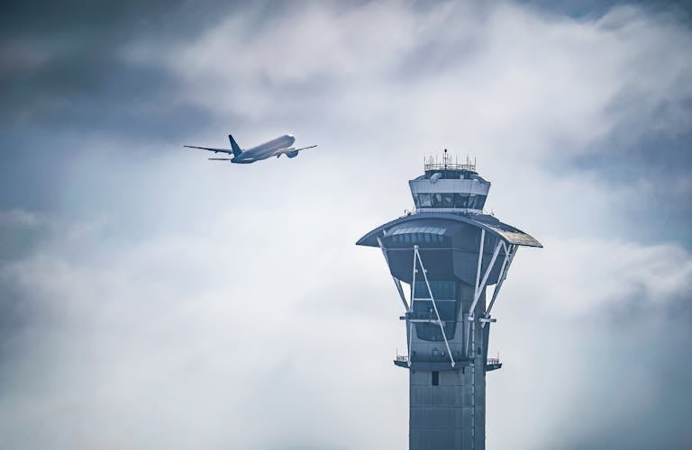 Dramatic shot of an airplane taking off near the iconic LAX control tower in Los Angeles, California.