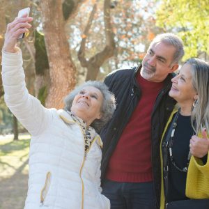 Group of cheerful seniors taking a selfie together outdoors, capturing a moment of joy.